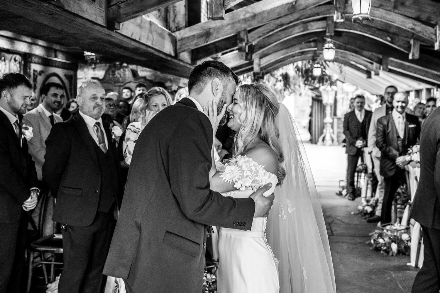 Black and white photo of the first kiss in the Enchanted Chapel at Newton Hall, guests clapping