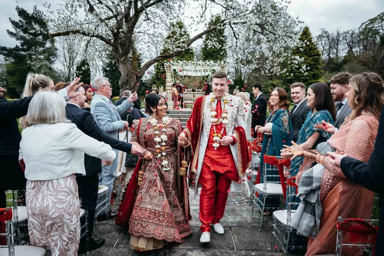 Couple walking back through cheering guests after their garden ceremony at Lartington Hall