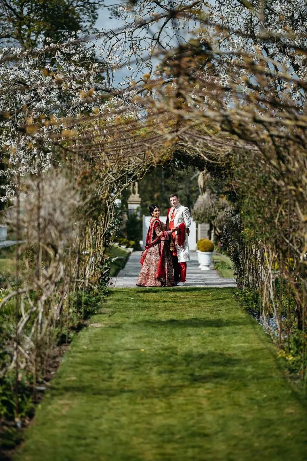 Couple at the end of a green tree tunnel in the grounds of Lartington Hall