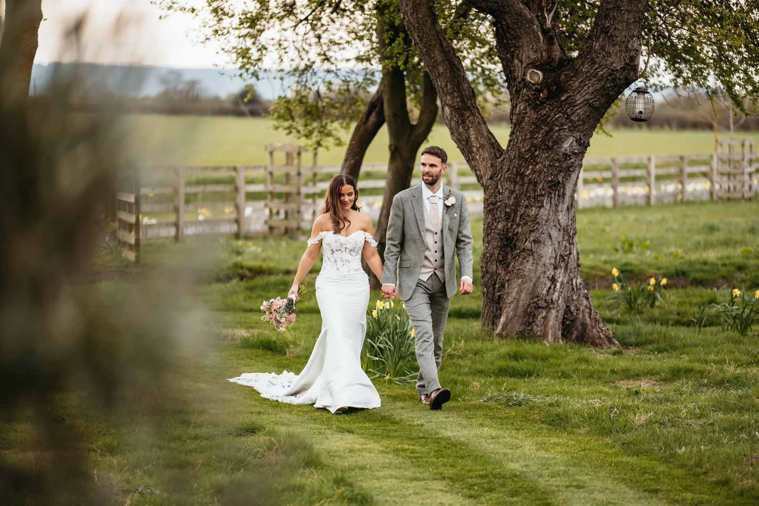 Couple walking under the old trees in the grounds of Thirsk Lodge Barns