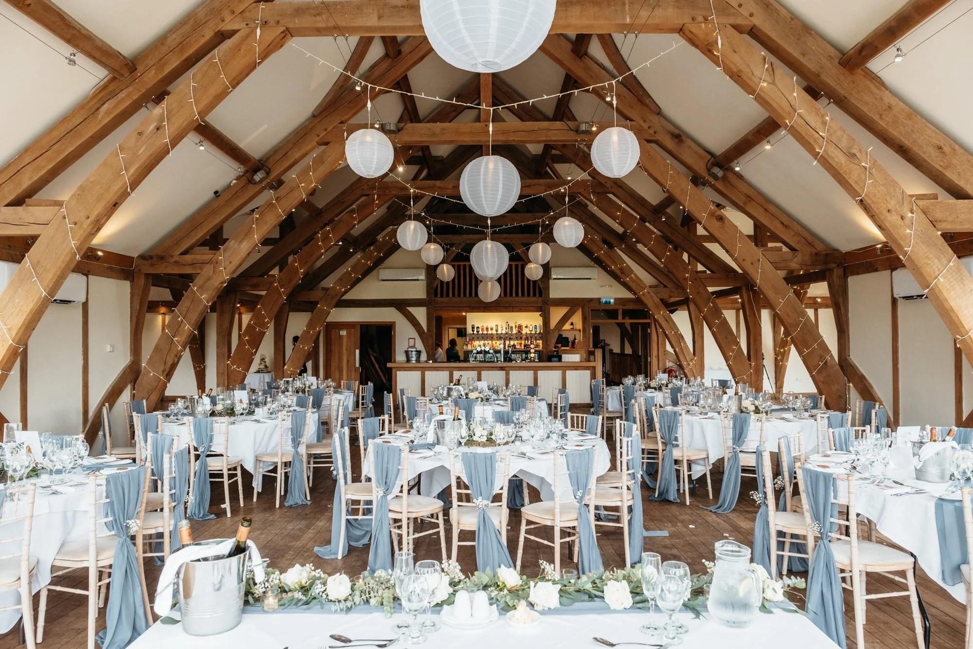 Oak-framed reception room at Sandburn Hall set with round tables and paper lanterns