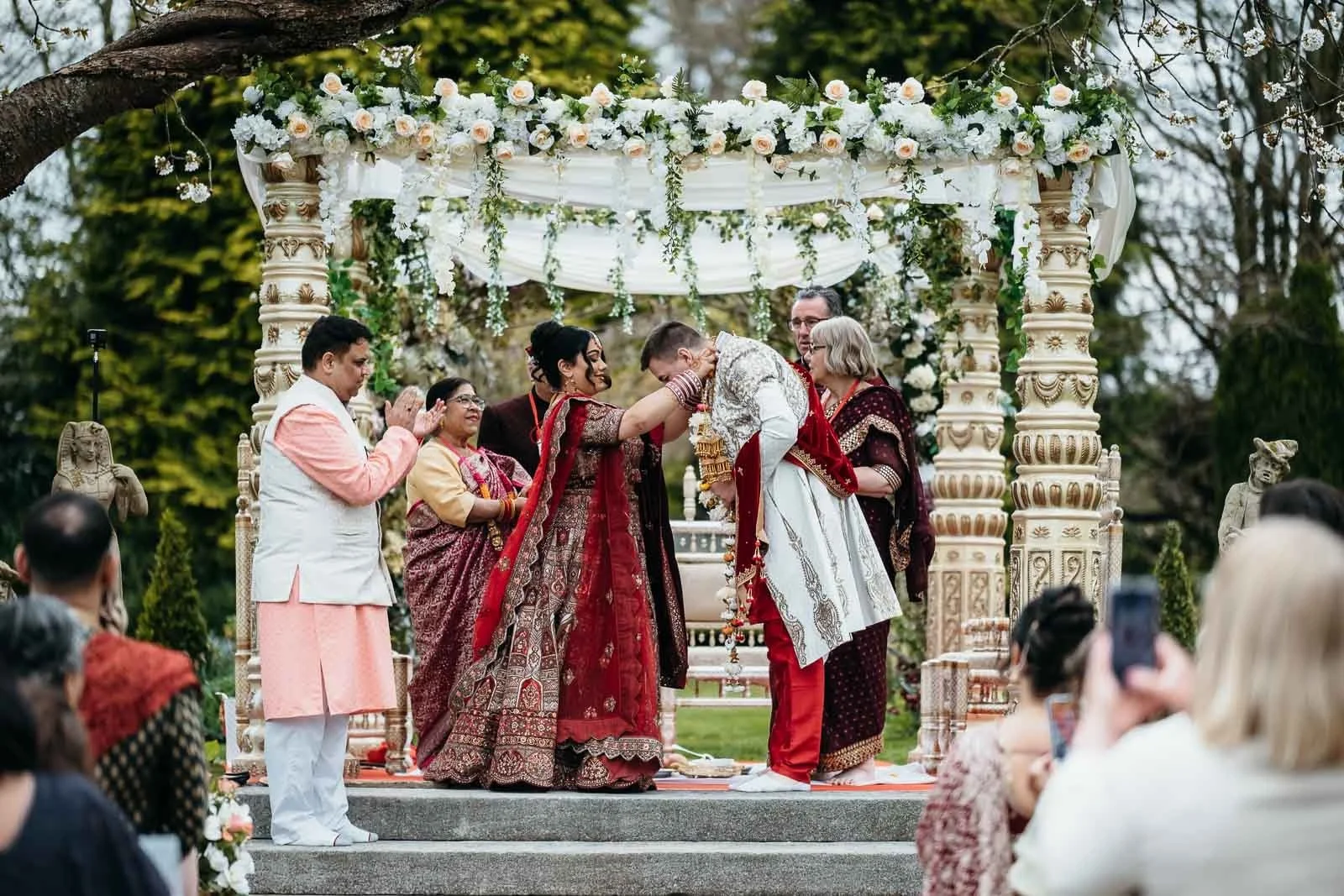 Wedding ceremony under a white floral mandap in the gardens at Lartington Hall