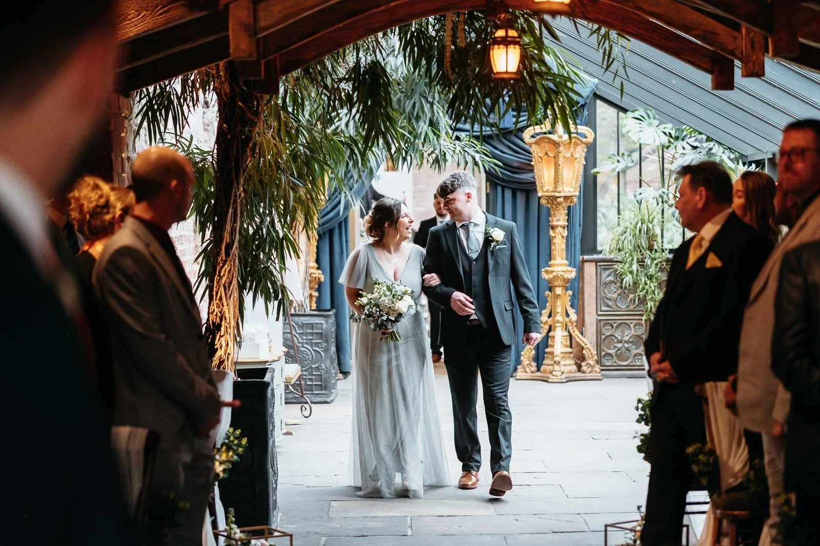 Aisle view of a ceremony in the plant-filled Enchanted Chapel at Newton Hall, Northumberland