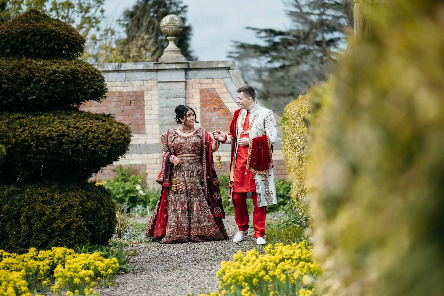 Couple among the clipped topiary and yellow flowers in the formal gardens at Lartington Hall