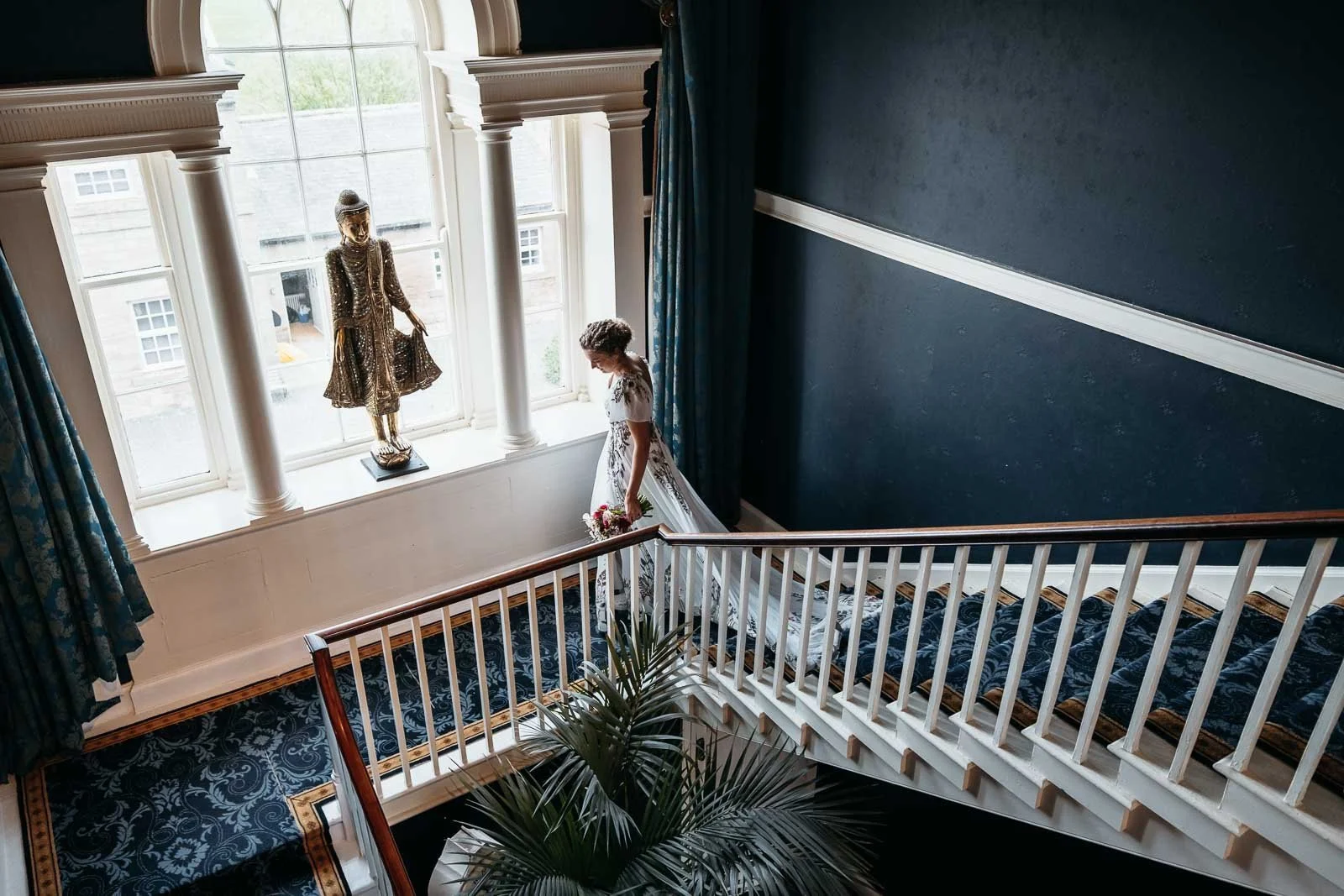 Bride on the staircase in window light inside Newton Hall