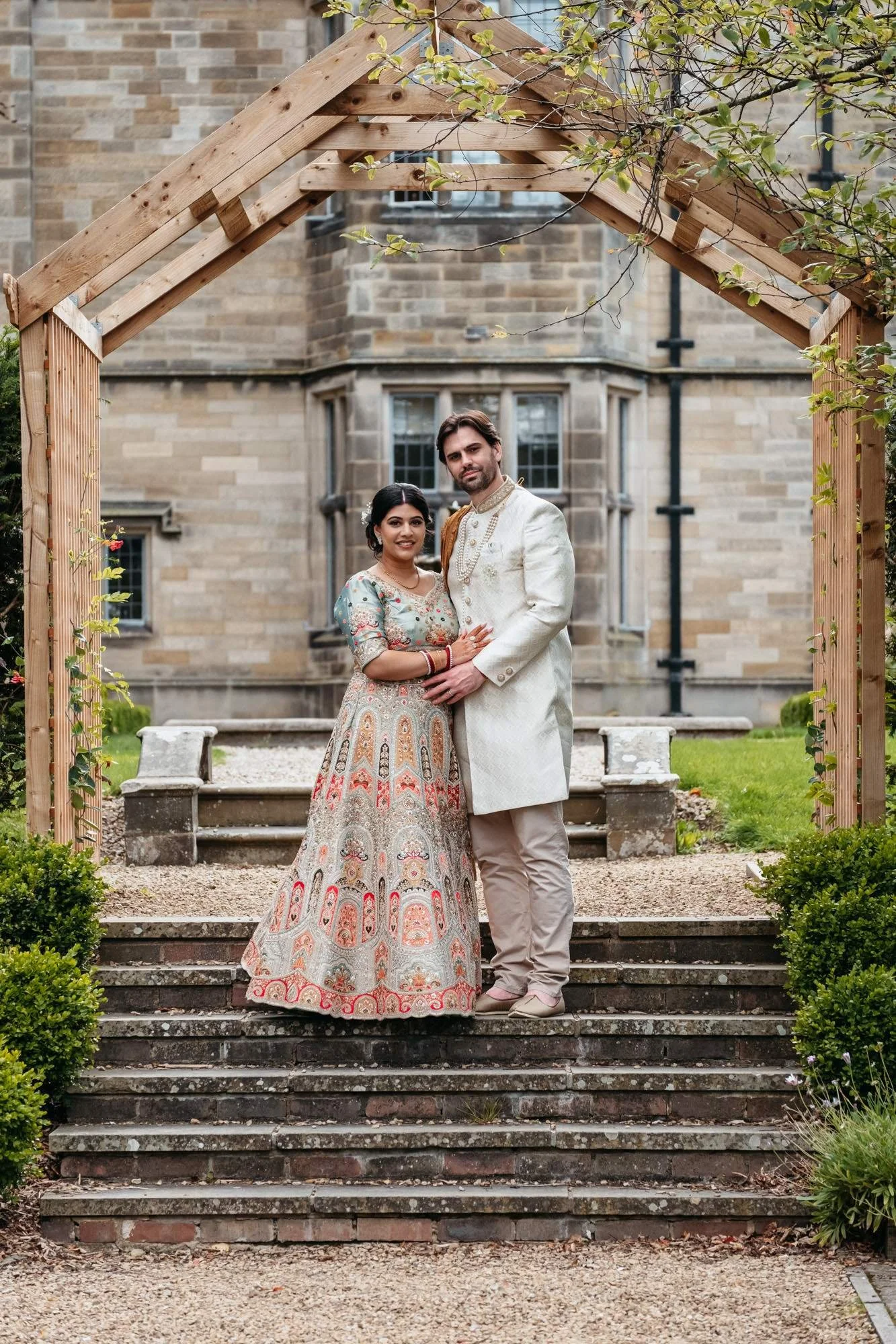 Couple on the stone steps under the timber arch in the gardens at Gisborough Hall