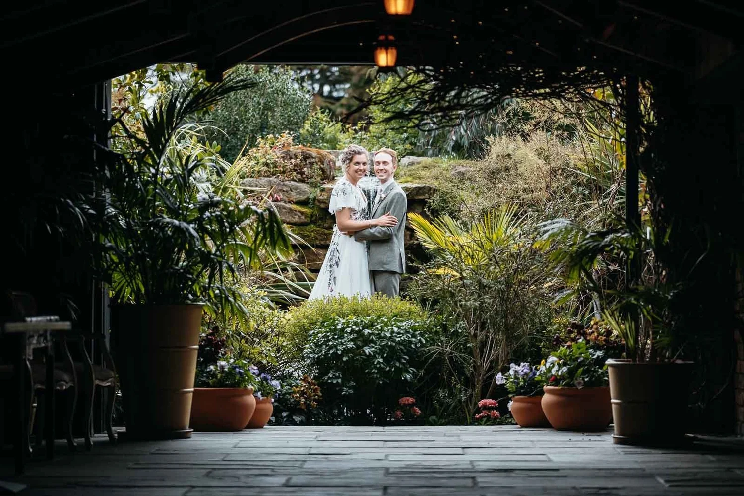 Couple framed through a dark stone archway in the gardens at Newton Hall
