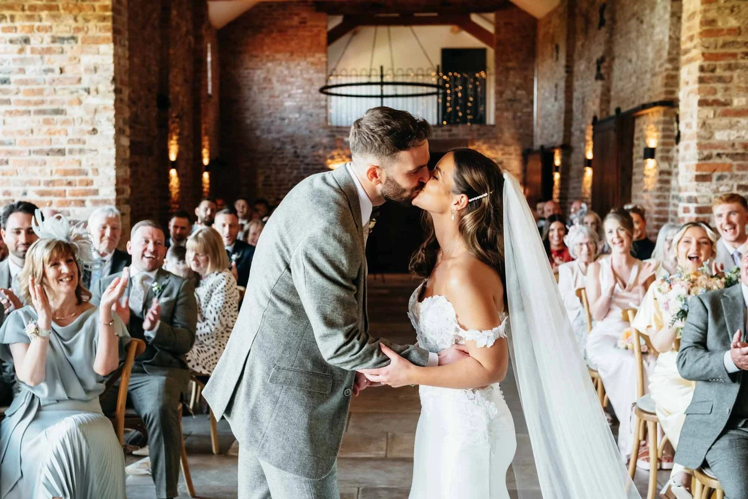 Couple hugging guests in the brick courtyard during the drinks reception at Thirsk Lodge Barns
