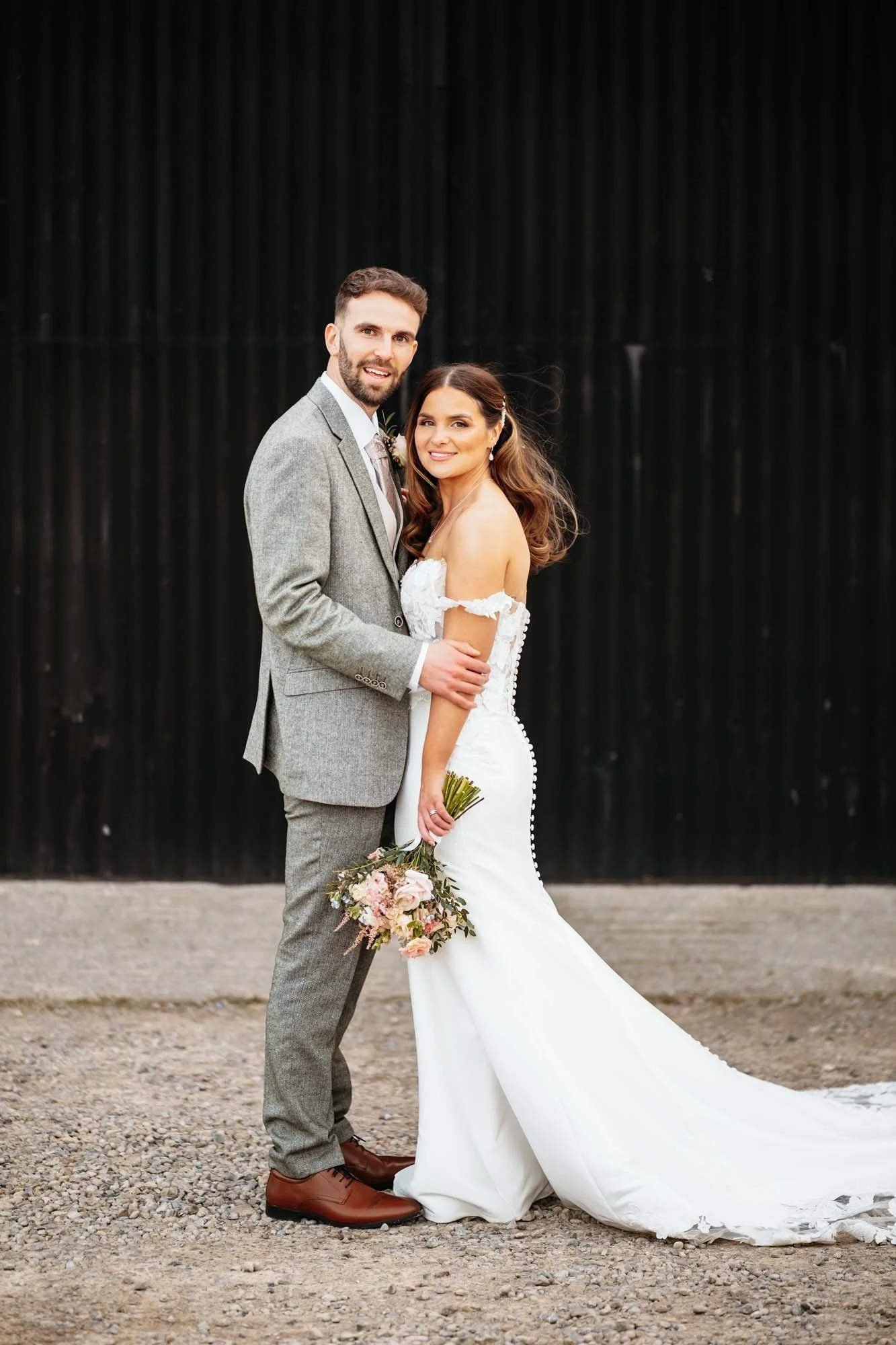 Full-length portrait of a couple against black barn doors at Thirsk Lodge Barns