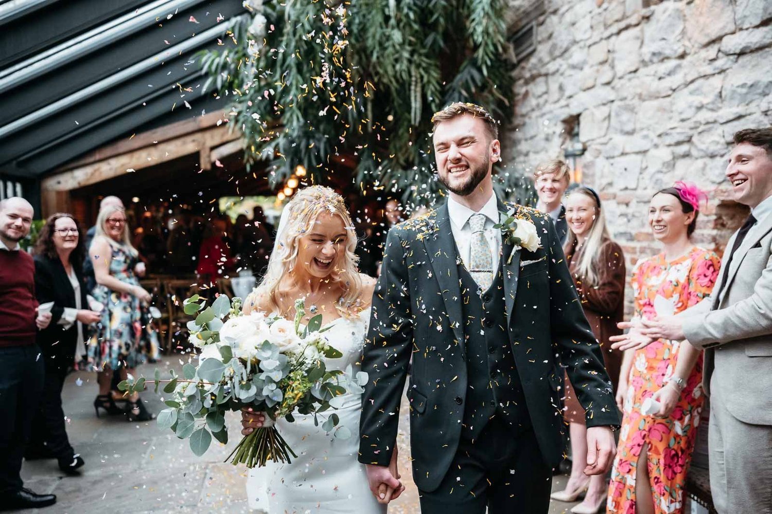 Couple at the end of the aisle in the Enchanted Chapel at Newton Hall, guests and greenery around