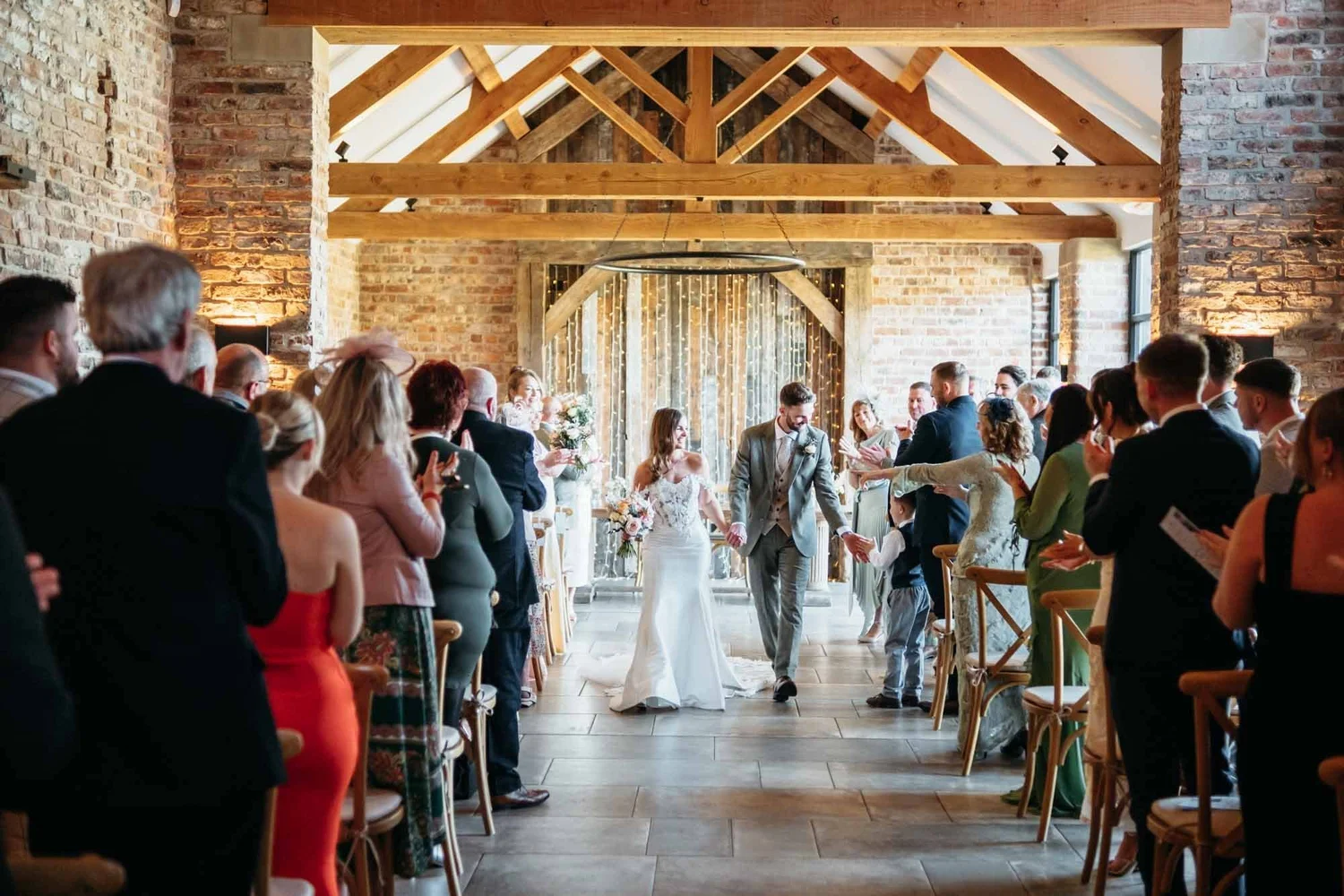 Guests seated for a civil ceremony in the oak-beamed Main Barn at Thirsk Lodge Barns