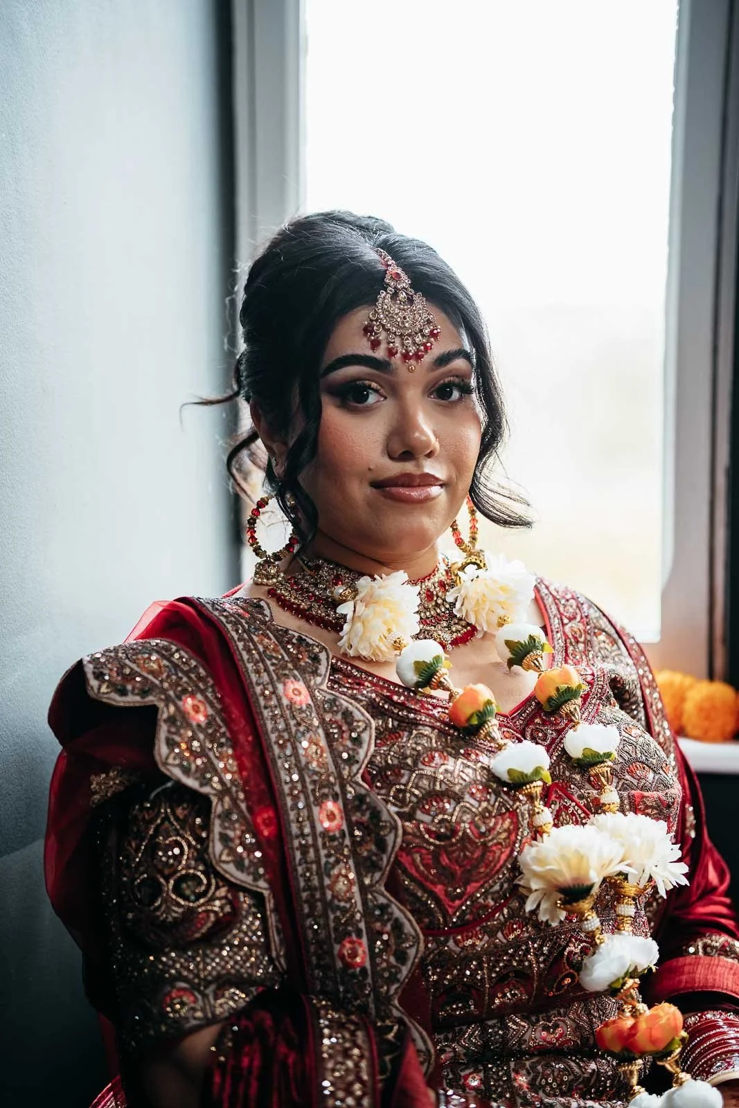 Close portrait of a bride wearing flower garlands by a window at Lartington Hall