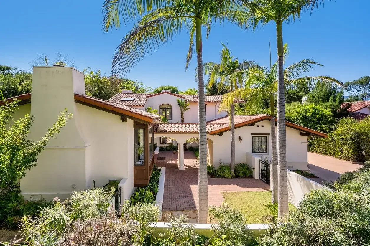 Spanish-style home with a clay tile roof surrounded by palm trees