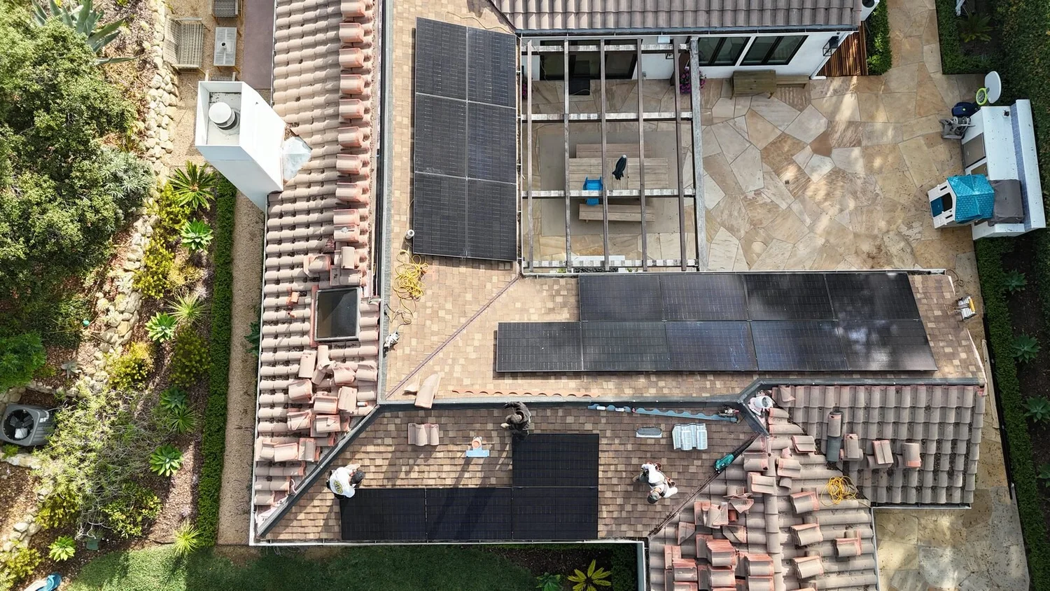 Crew relaying clay tile around new solar panels on a Santa Barbara home