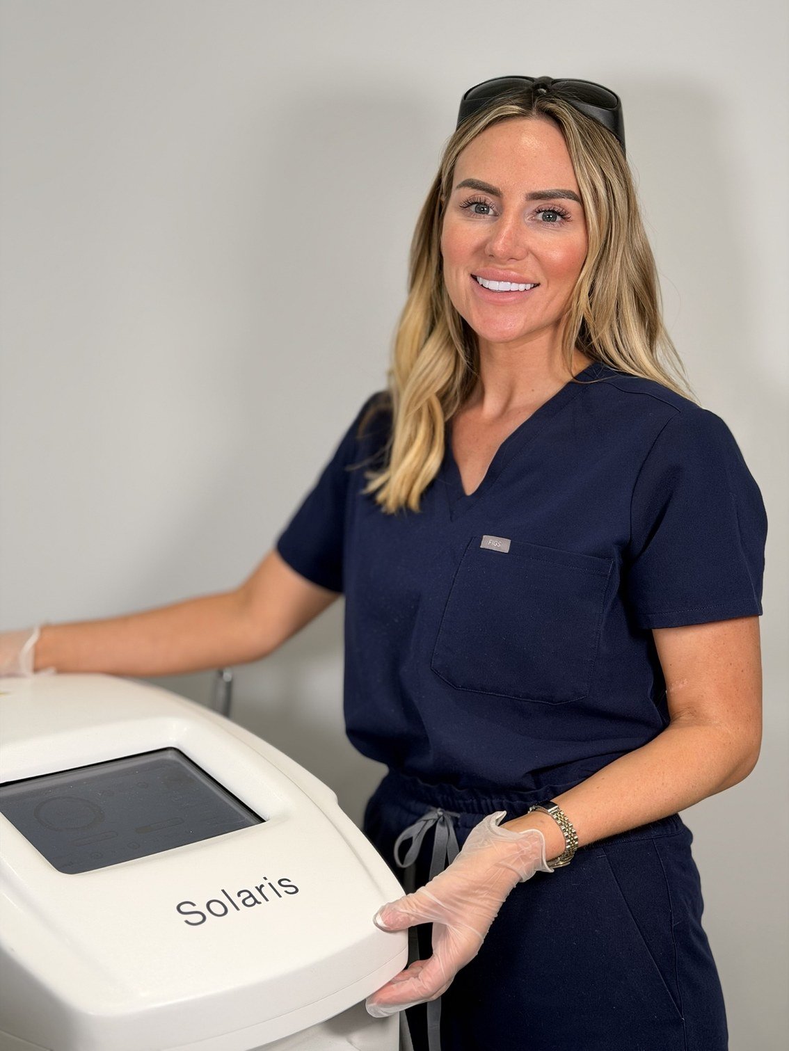 Laser practitioner in navy scrubs beside a Solaris laser machine