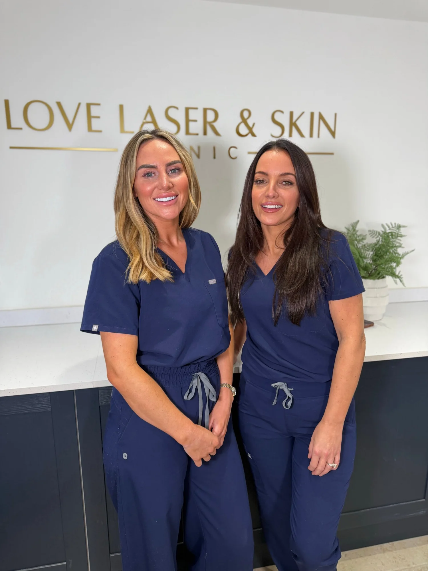 Laura (left) and Helen (right) in navy scrubs in front of the Love Laser & Skin Clinic sign