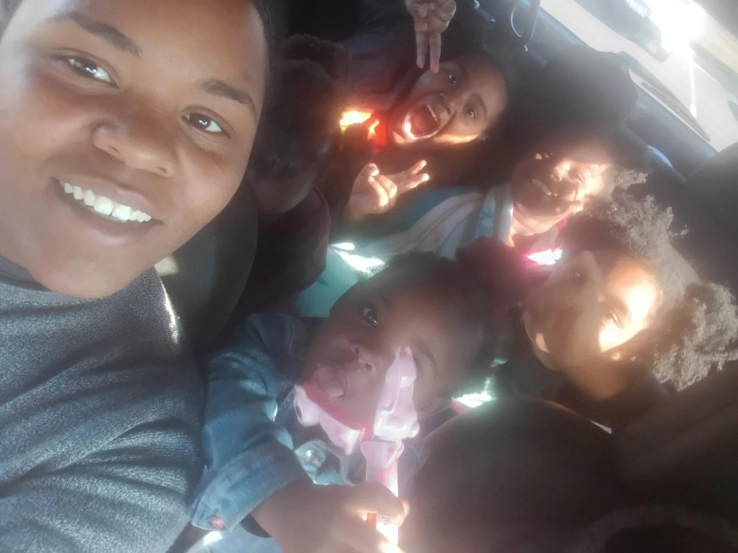 A mom and her children smiling in their car