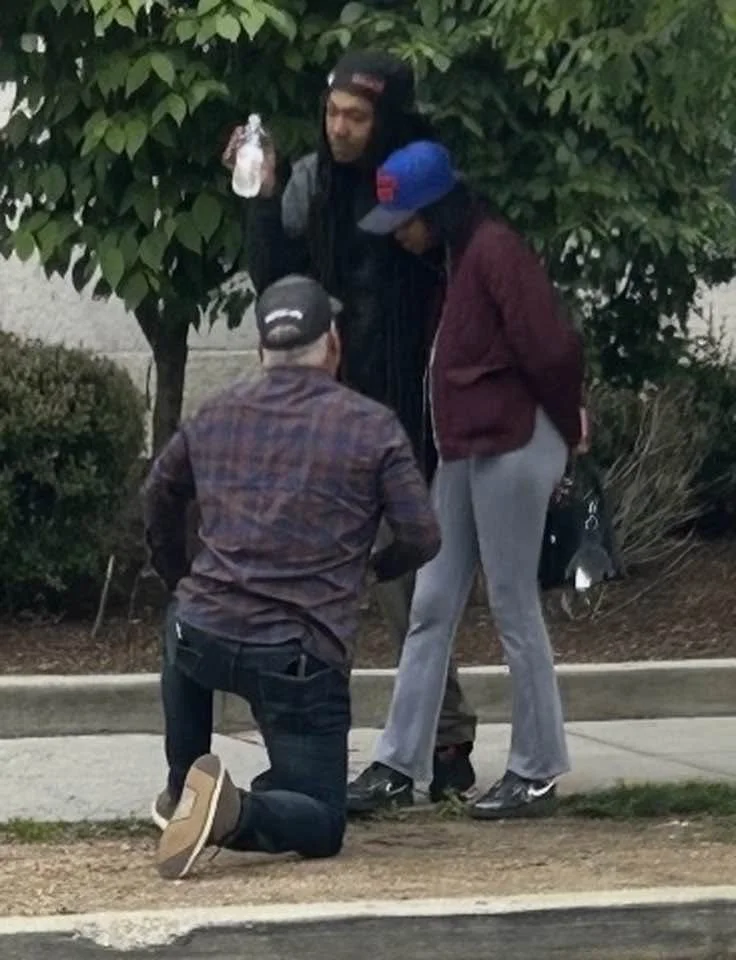 Scott kneeling on the sidewalk to talk with a young mom