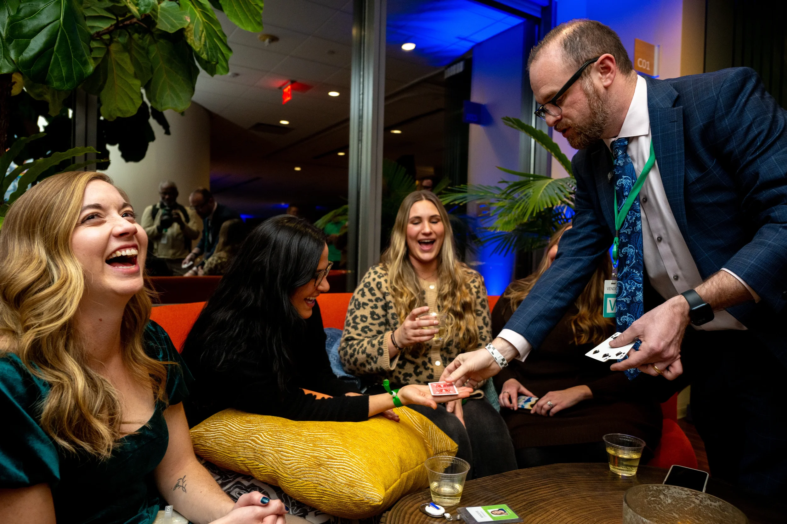 Magician performing card magic for a group of guests on a couch