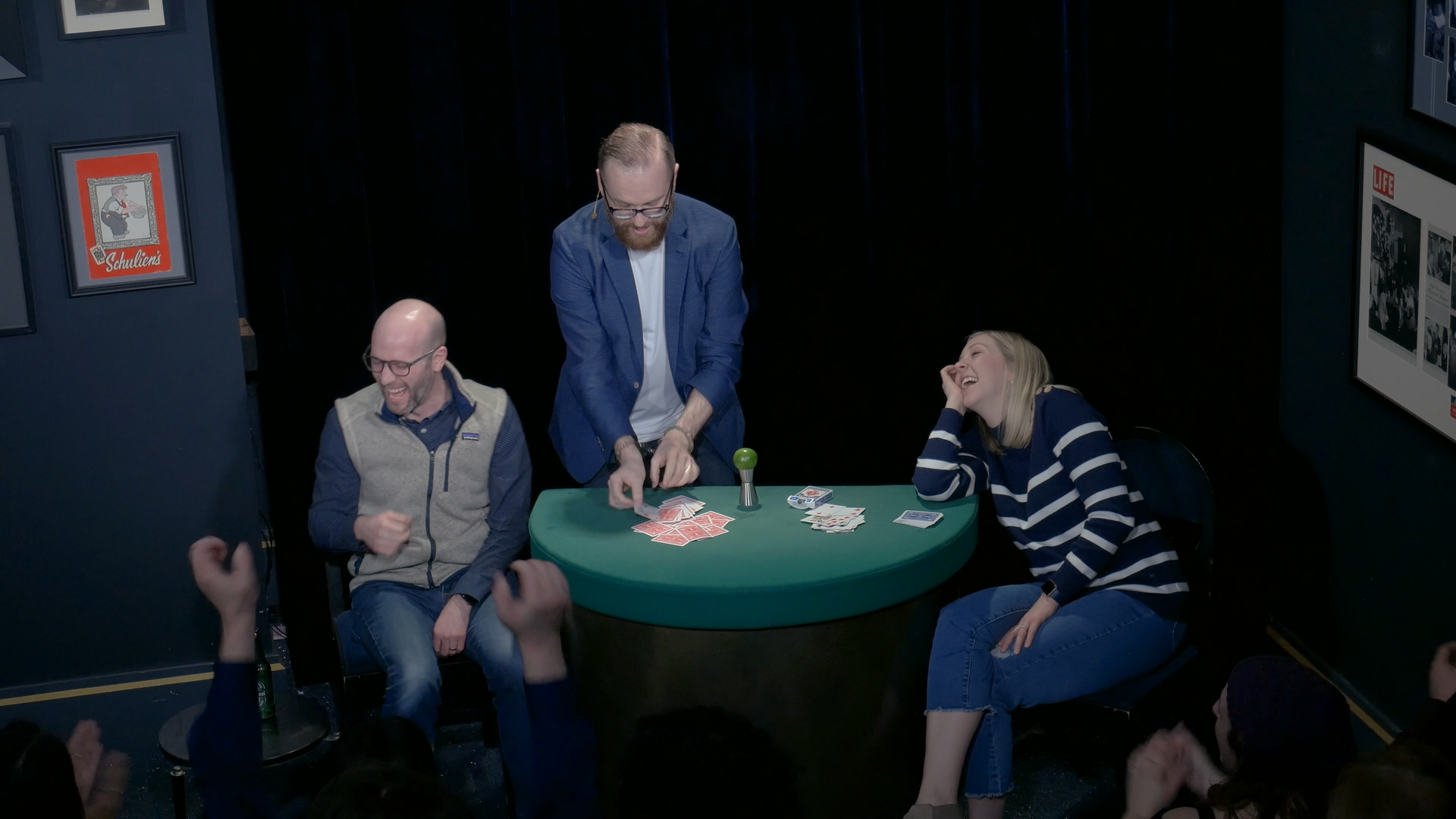 Audience with hands raised cheering at a theater magic show