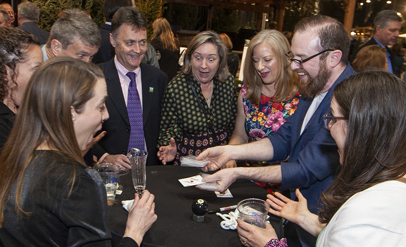 Magician performing close-up magic for guests at an event