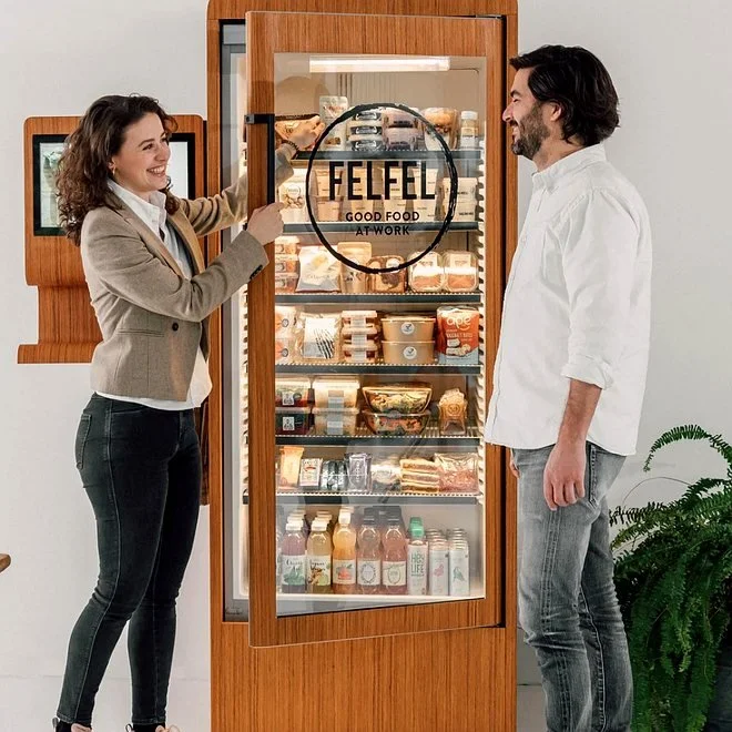 Zwei Mitarbeitende am offenen FELFEL Kühlschrank im Büro