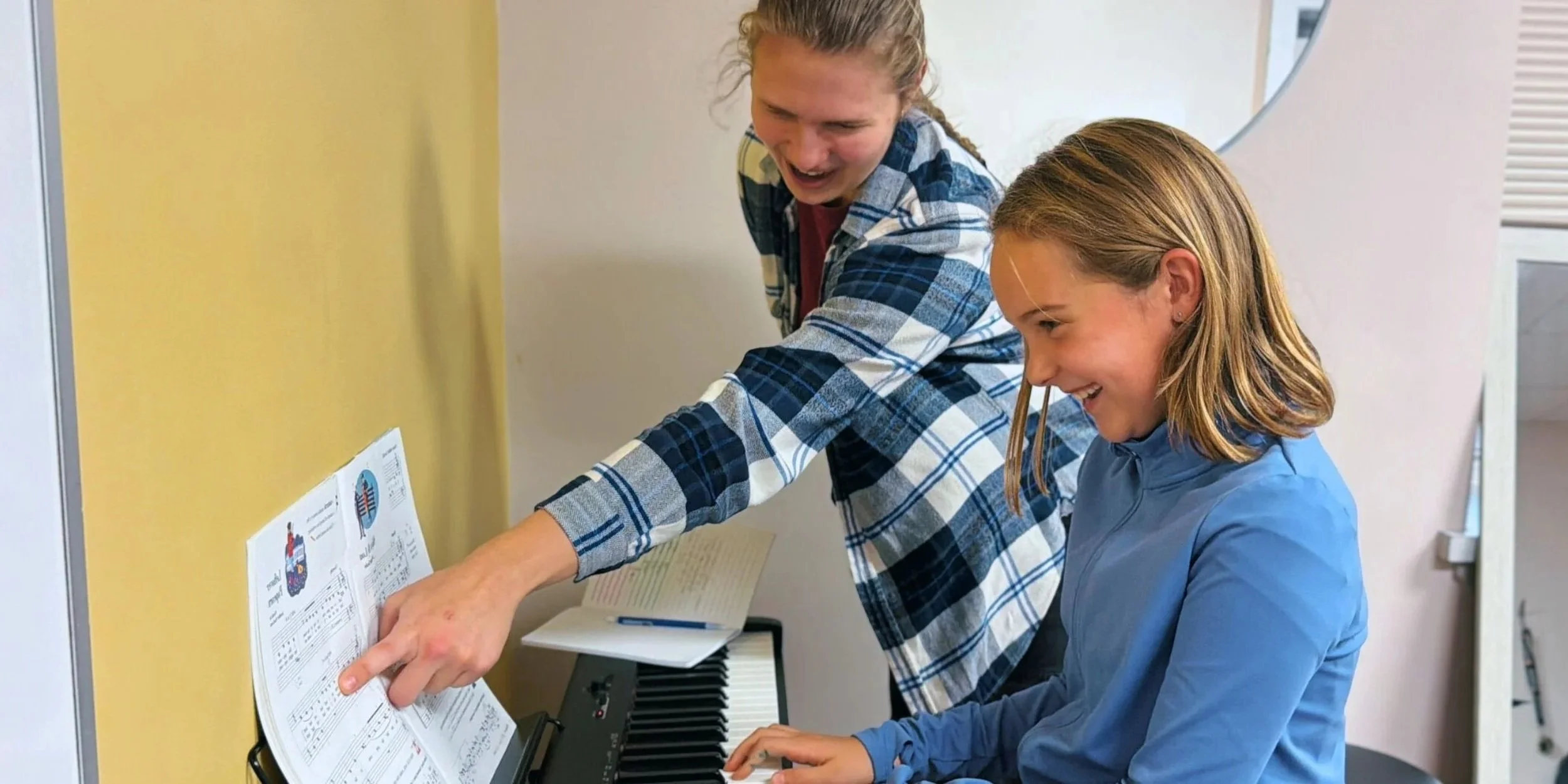A Yellow Brick Music instructor helping a young student during a piano lesson