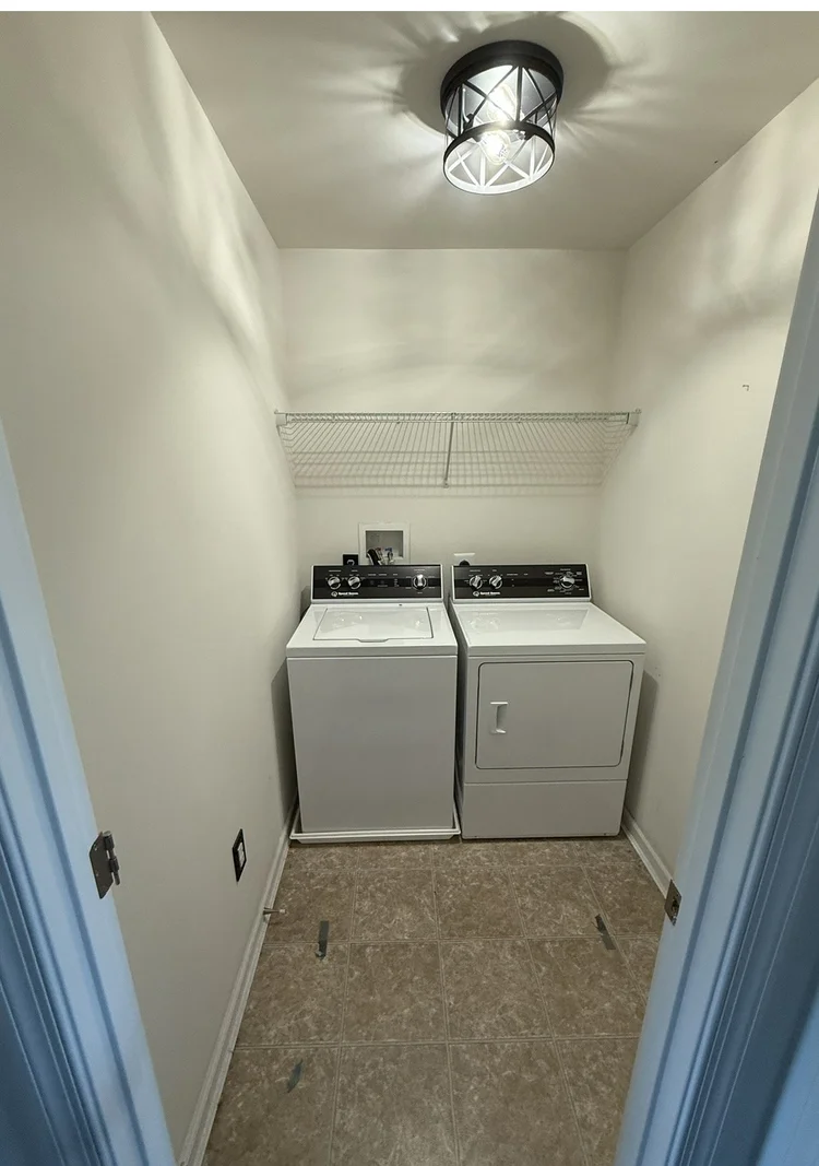 Laundry room with white walls and washer and dryer before accent wall