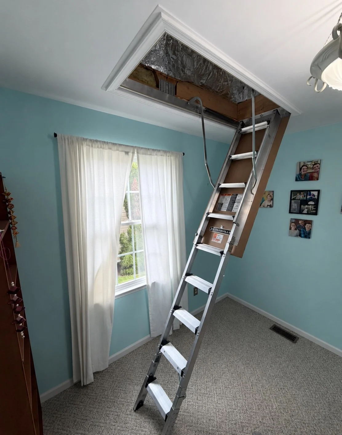 Completed pull-down attic ladder with white trim in a blue room