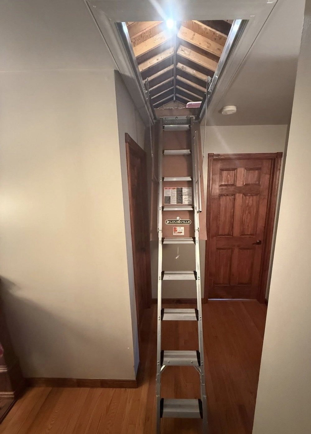 Completed attic access ladder near wood doors