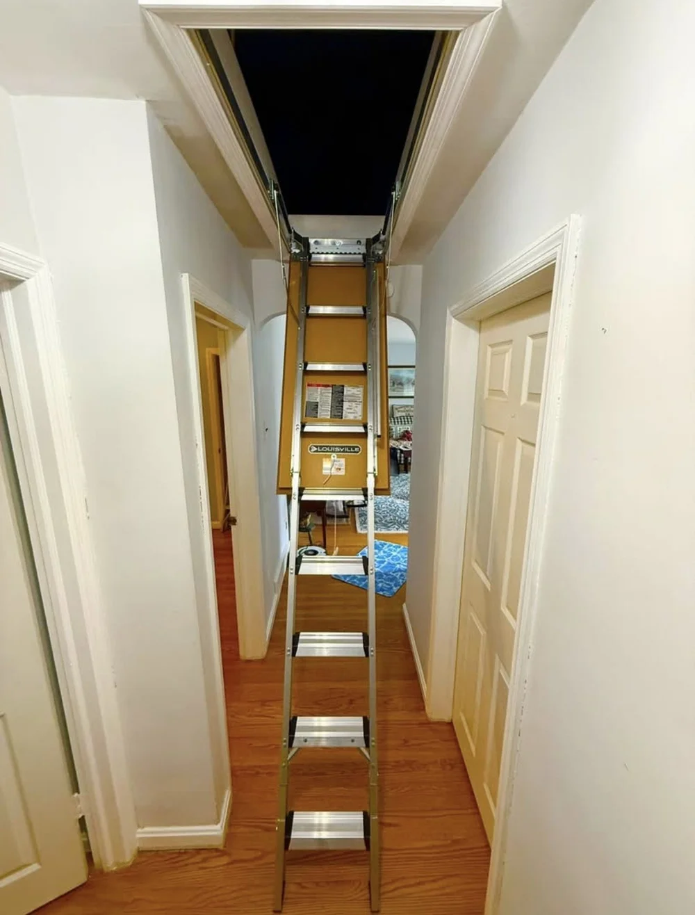 Completed attic ladder installation in a white hallway