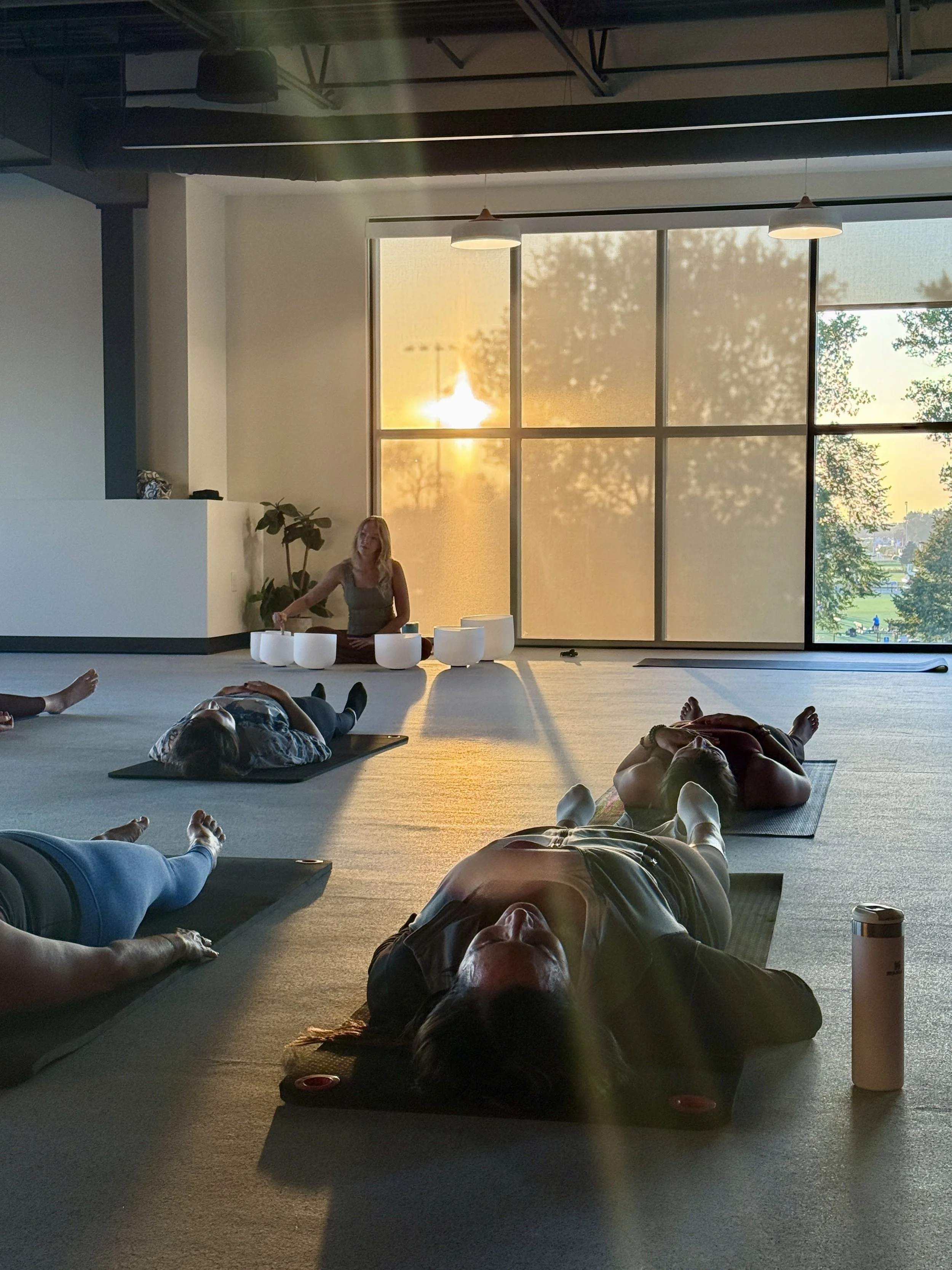 A team resting on mats during an on-site sound bath at sunset