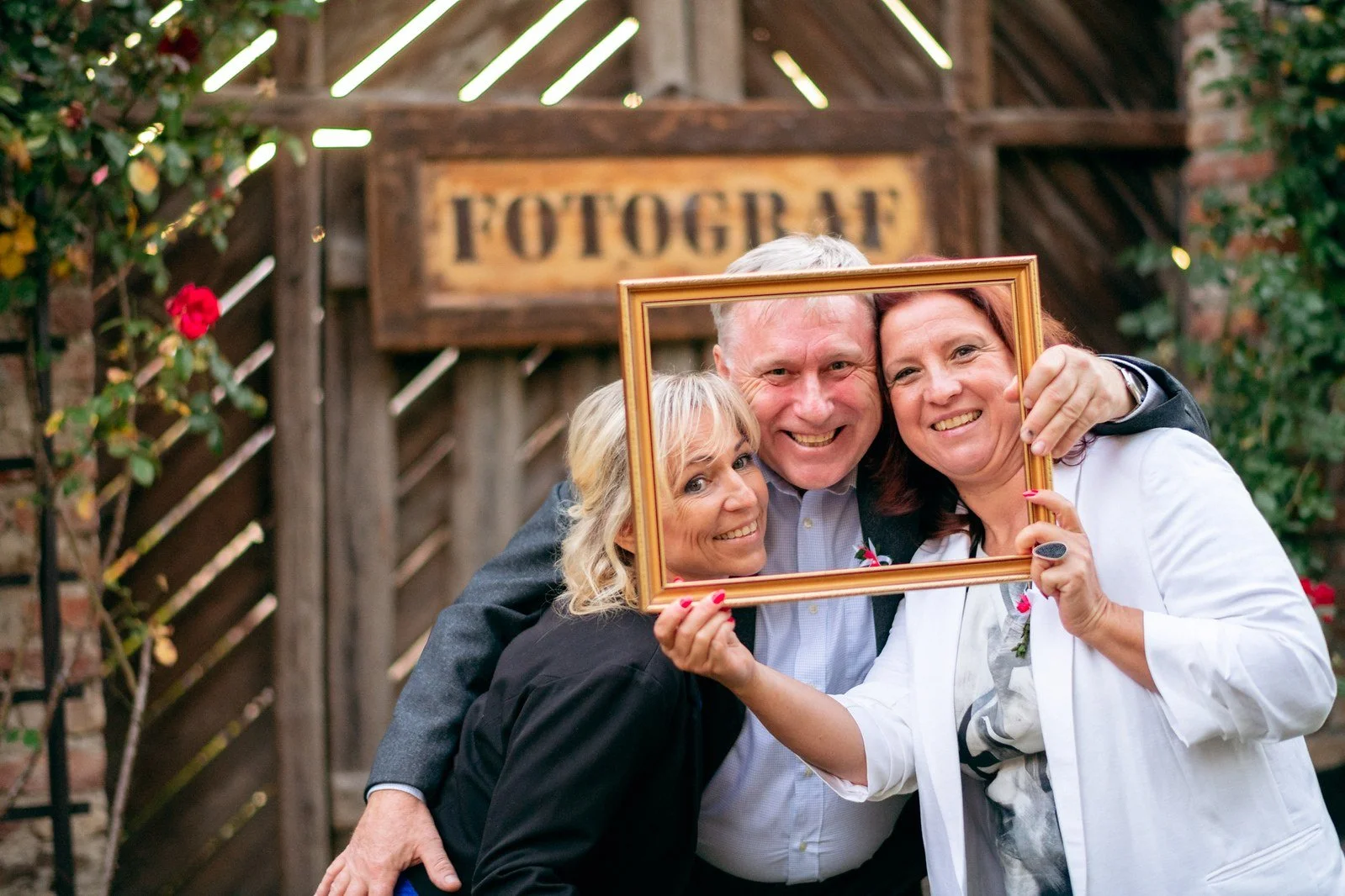 Dvě ženy pózují s velkým dřevěným rámem před vstupem označeným jako fotokoutek.