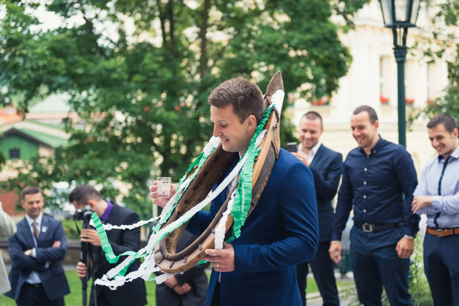 Ženich se směje během venkovního svatebního zvyku se stuhami.