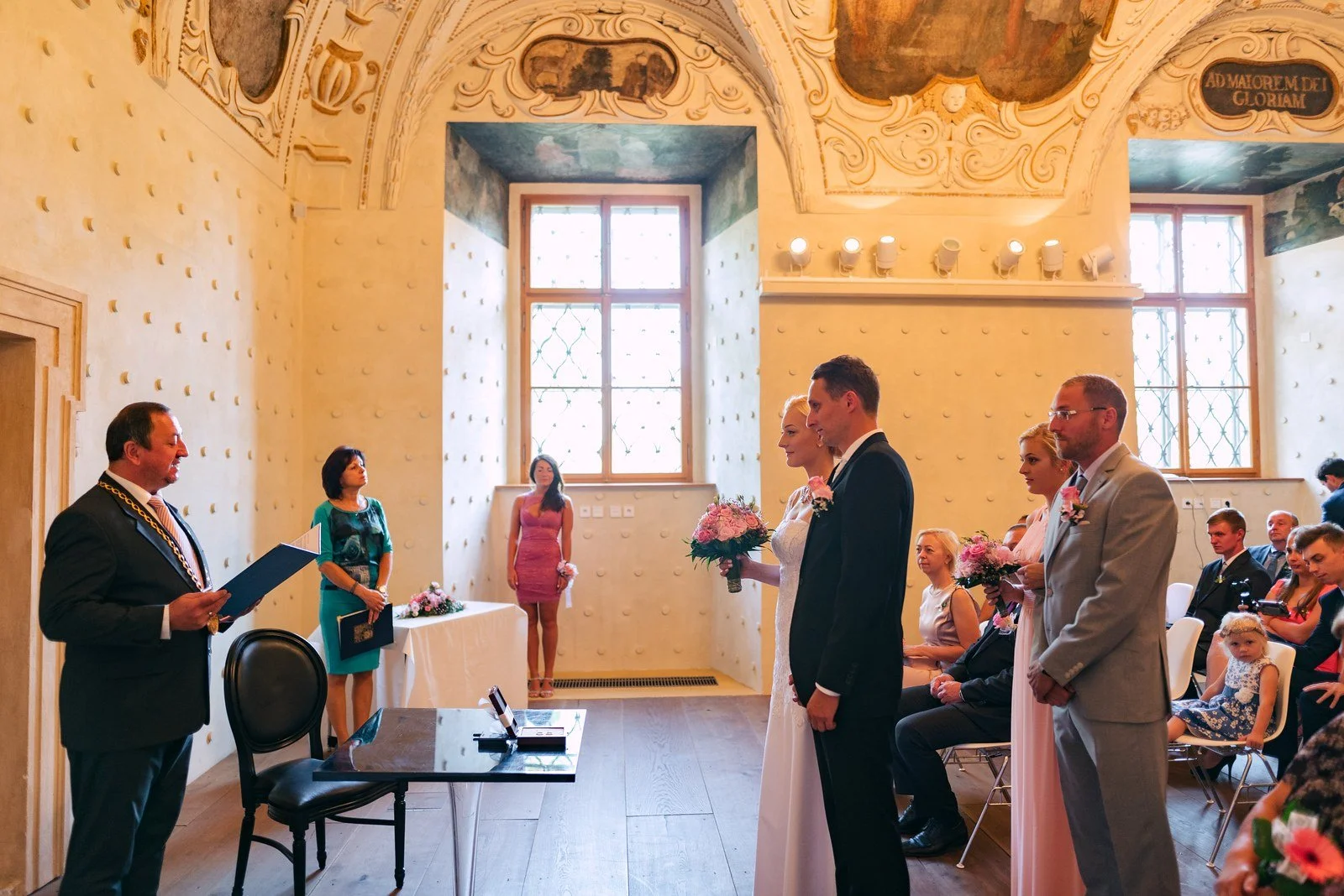 Dvojice stojí u obřadního stolu naproti osobě vedoucí obřad.