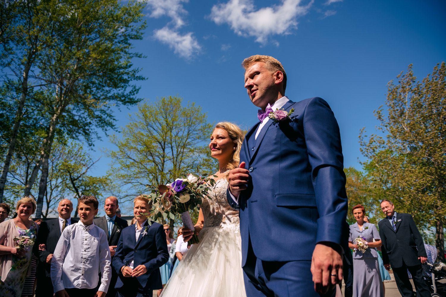 Novomanželé vycházejí mezi hosty po společném fotografování během svatby Roman a Sára v Penzionu a Pivovaru Nový Rybník u Obořiště.
