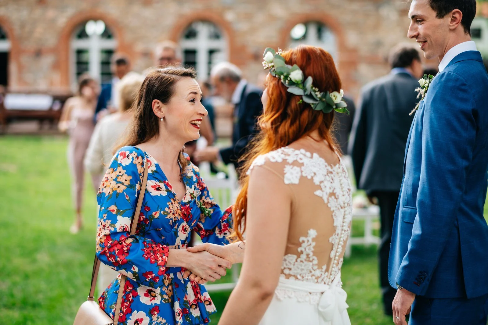 Žena v květovaných šatech hovoří s nevěstou během gratulací.