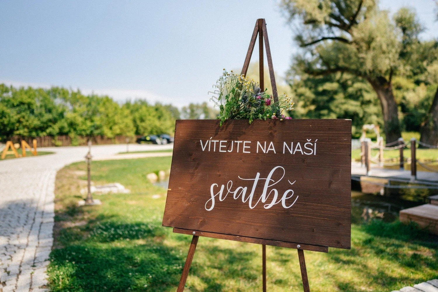 Dřevěná cedule Vítejte na naší svatbě zavěšená u cesty