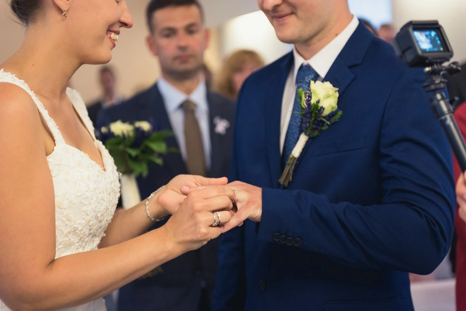 Detail rukou při navlékání snubního prstenu ženichovi.