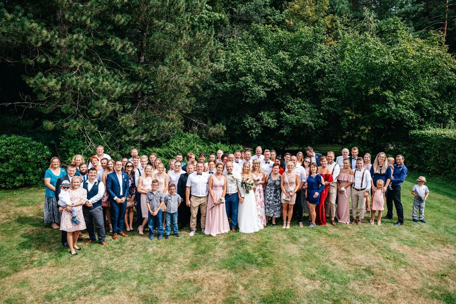 Velká skupinová fotografie hostů na trávníku.