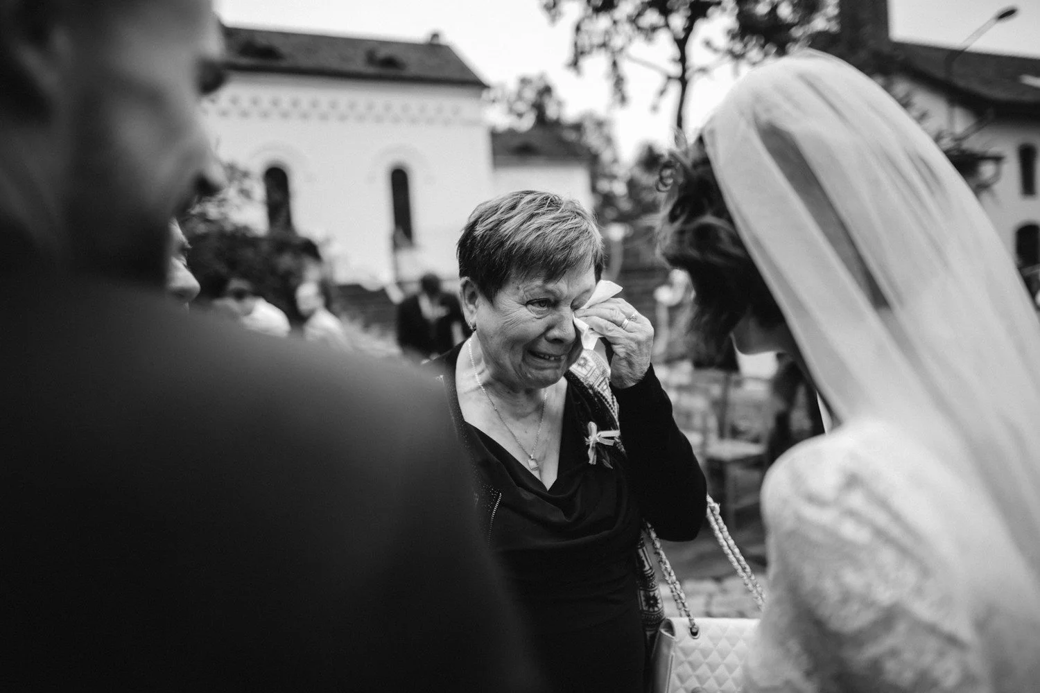 Černobílý záběr ženy otírající si oko při setkání s nevěstou.