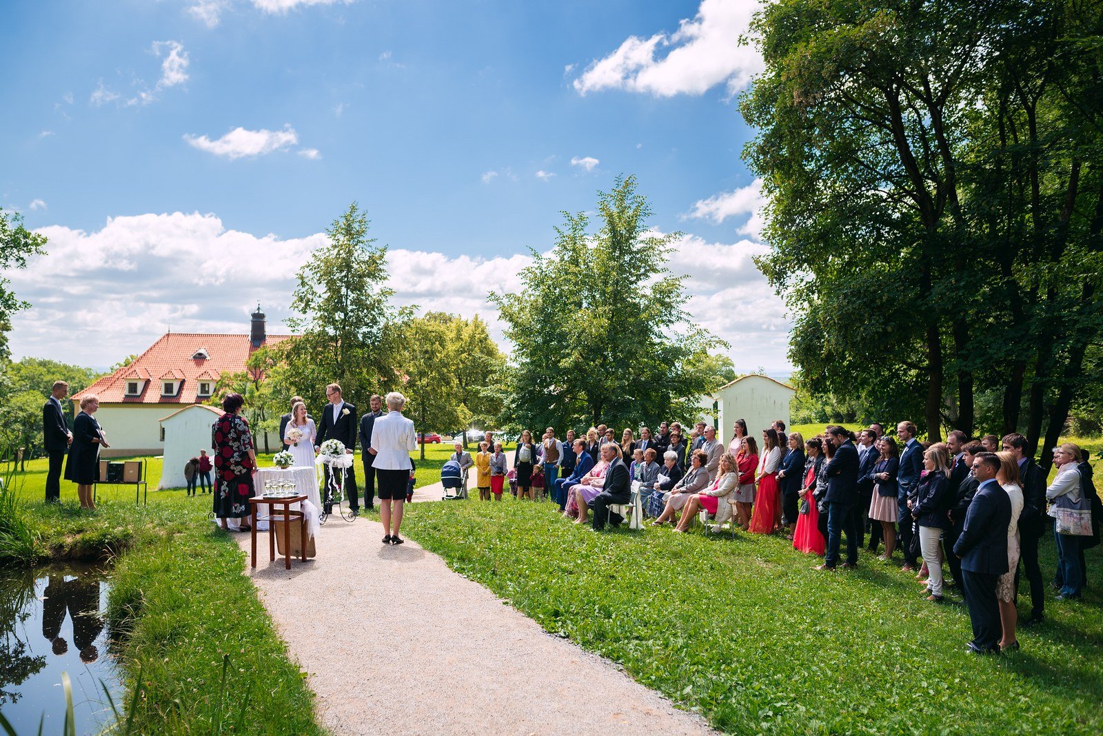 Muž v šedé vestě a bílé košili hledí z profilu k prosvětlenému oknu.
