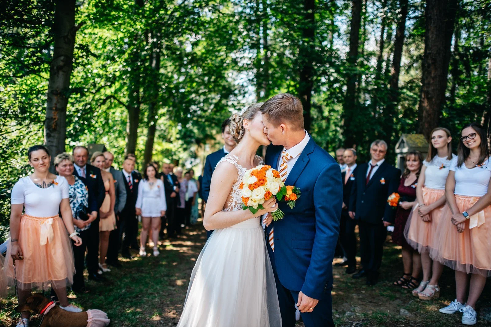 Novomanželé se líbají pod bílou obřadní výzdobou.