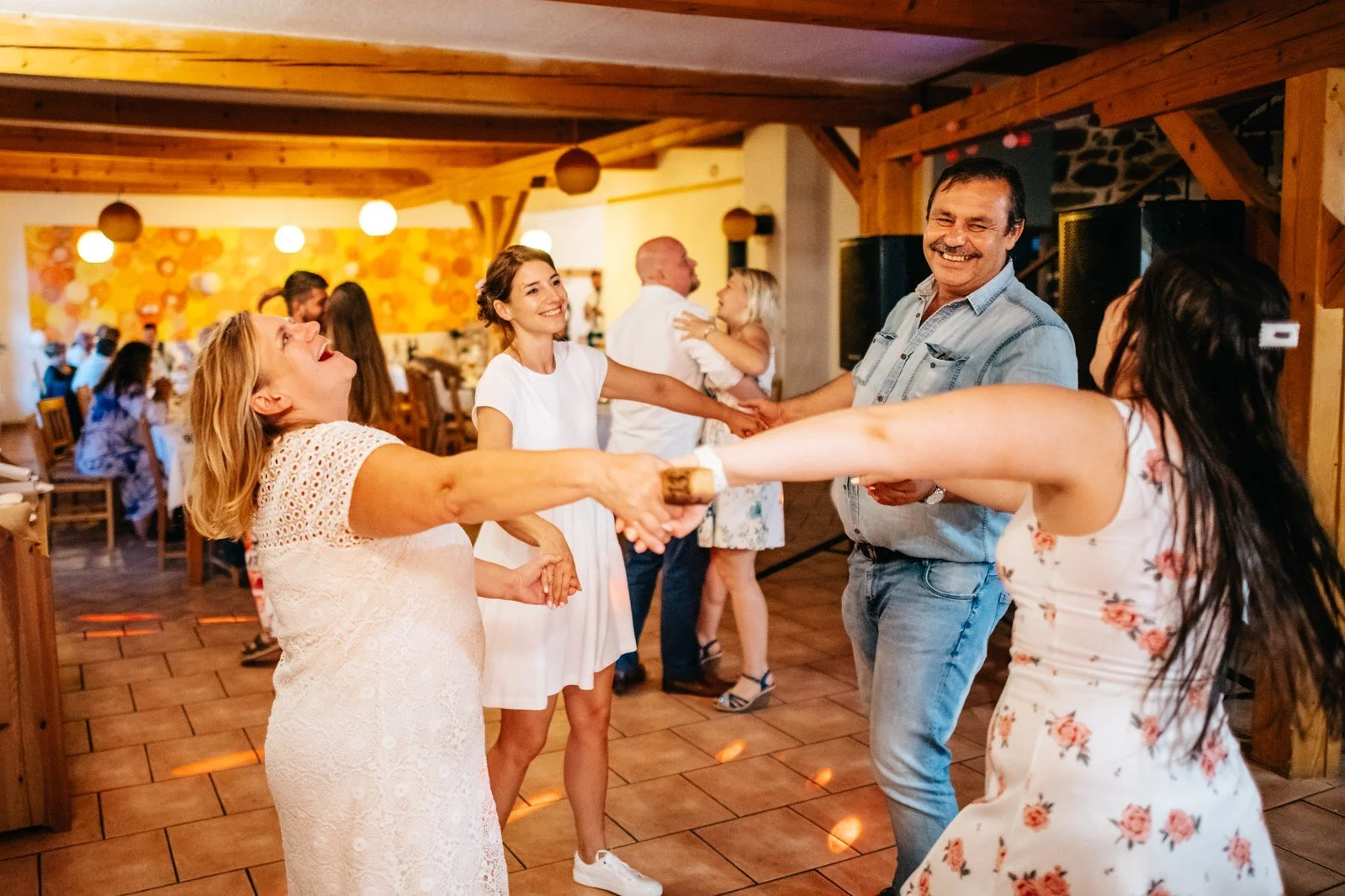 Skupina žen tančí s roztaženými pažemi.