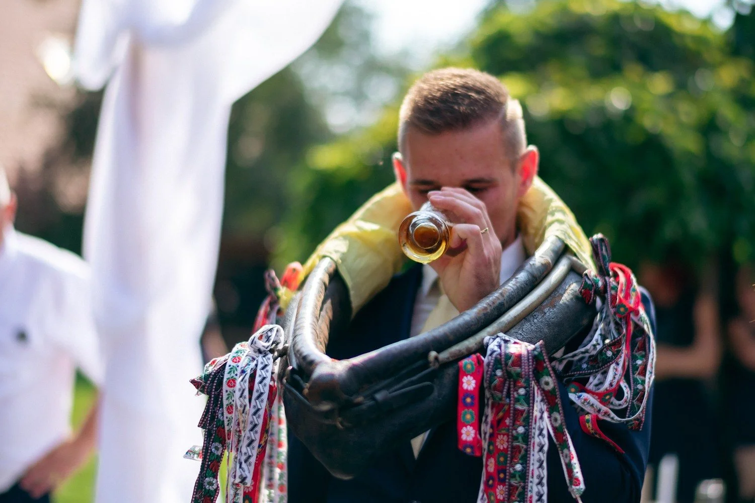 Ženich pije z nádoby obtočené barevnými stuhami