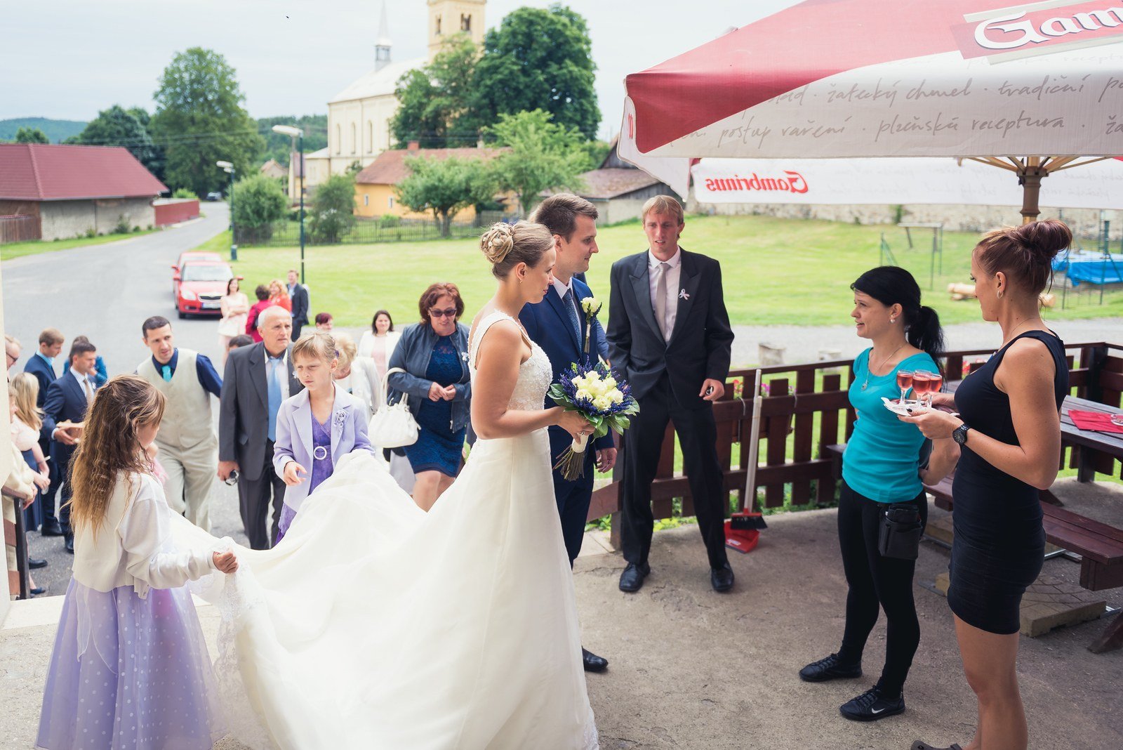 Hosté vítají novomanžele potleskem před hostinou.