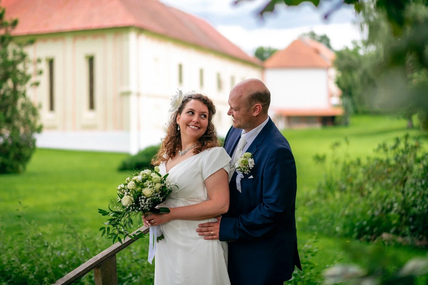Pár pózuje před světlou zámeckou budovou.
