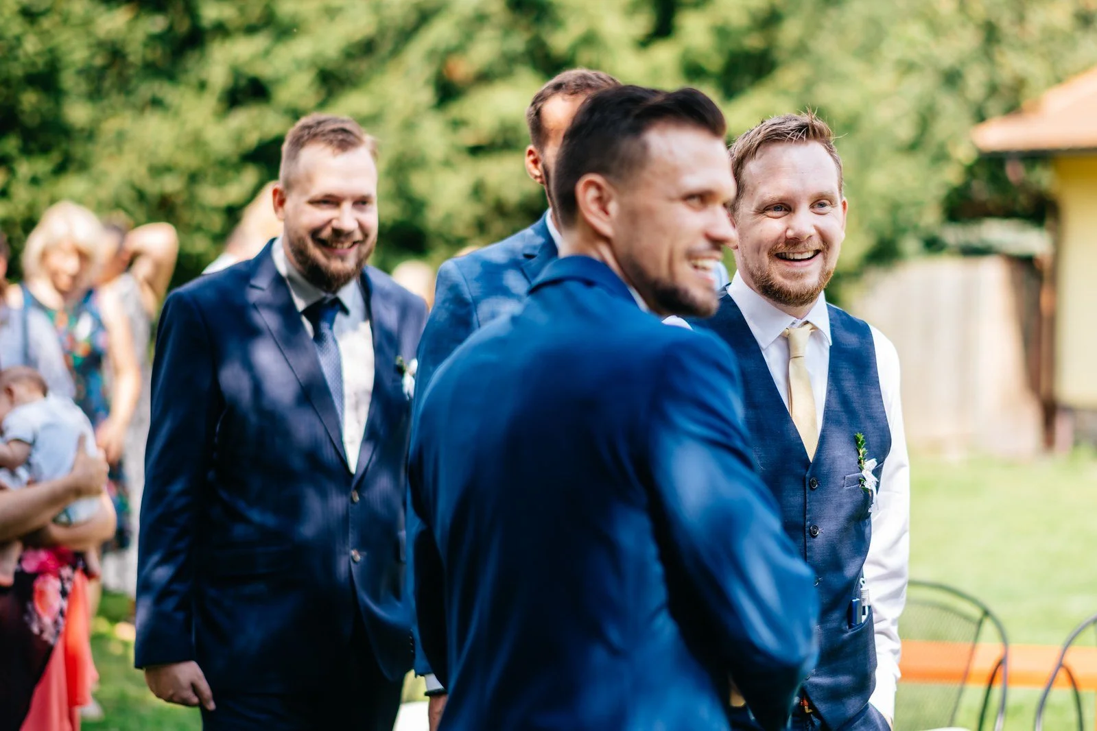 Skupina mužů se směje při společné fotografii.