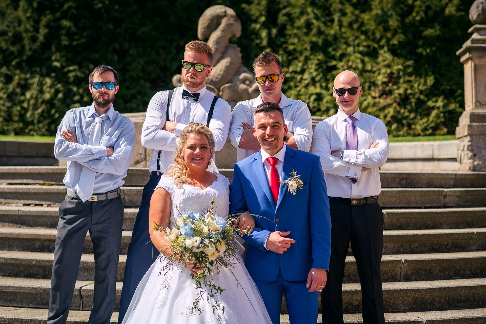 Hosté zvedají novomanžele během skupinového fotografování.