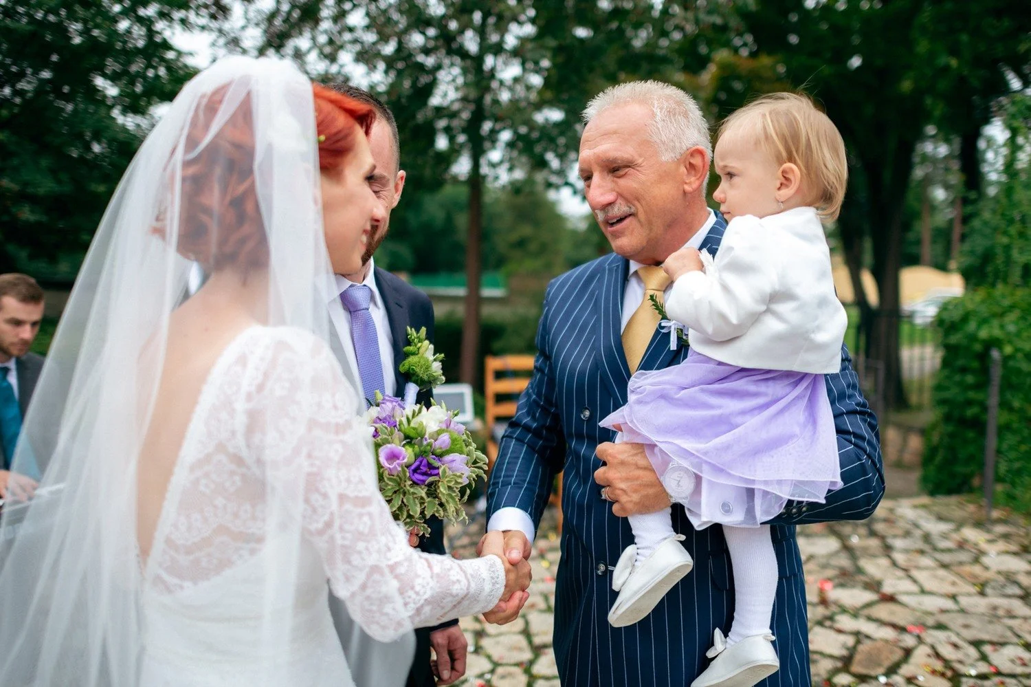 Martina v závoji stojí u staršího muže, který drží malé dítě.